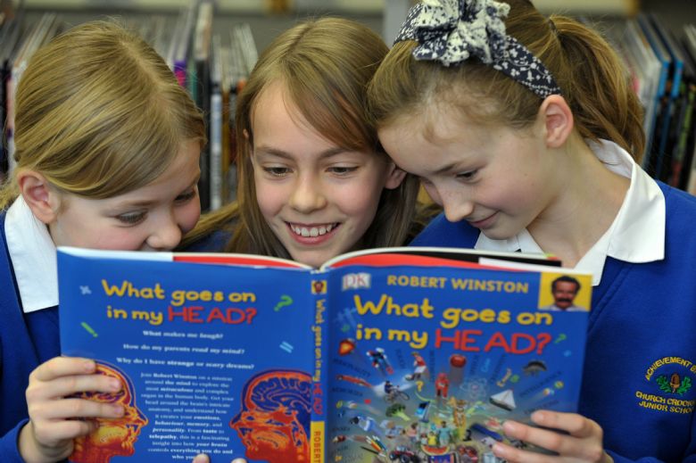  3 children enjoying a book in the library